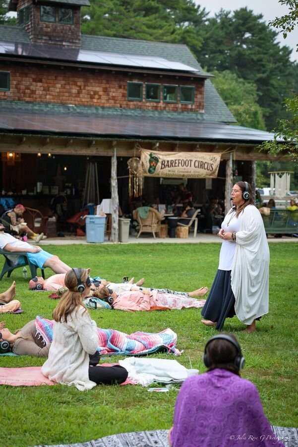 A sound session on the grass in front of the lodge, people lying on blankets